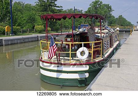 Stock Photography - Charter boat in lock, while two men attend to lines; Pittsford, New York, United States of America. Fotosearch