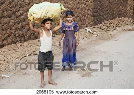 Stock Photography - Children In Front Of A Wall With Cow Dung Patties, Patna, Bihar, India. Fotosearch