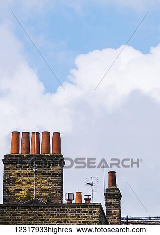Stock Photograph - Chimneys against a blue sky with cloud; London, England. Fotosearch