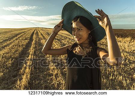Stock Photograph - Chinese young woman walking in a wheat field; Madrid Spain. Fotosearch