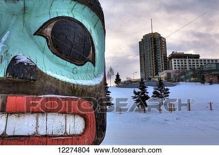 Picture - Close-up of a totem pole with the Hilton Hotel in the background, Downtown Anchorage, Southcentral Alaska, HDR. Fotosearch