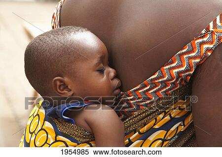 Stock Photography - Close-up of baby sleeping on woman's back in Bamako, Mali. Fotosearch