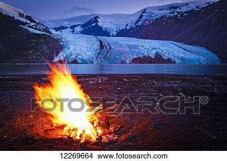 Picture - Close up of campfire in front of Portage Glacier at dusk, Chugach National Forest, Kenai Peninsula, Southcentral Alaska, Summer.. Fotosearch