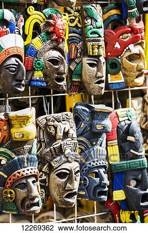 Stock Image - Close up of colourfully painted Mayan masks hanging on display; Akumal, Quintana Roo, Mexico. Fotosearch