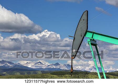 Close up of the head of a pump jack with green rolling hills, mountain range, blue sky and clouds in the background; Longview, Alberta, Canada View Large Photo Image Stock Photograph - Close up of the head of a pump jack with green rolling hills, mountain range, blue sky and clouds in the background; Longview, Alberta, Canada. Fotosearch