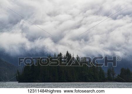 Stock Photograph - Clouds billow over the coastal mountains; Haida Gwaii, British Columbia, Canada. Fotosearch