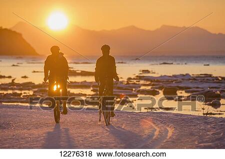 Couple bicycling in winter at sunset on the Tony Knowles Coastal Trail, Cook Inlet, Southcentral Alaska View Large Photo Image Stock Photo - Couple bicycling in winter at sunset on the Tony Knowles Coastal Trail, Cook Inlet, Southcentral Alaska. Fotosearch