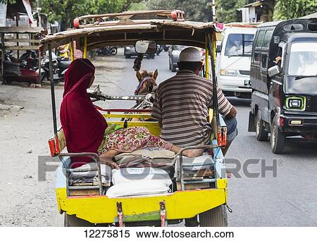 Couple on a cidomo, a horse-drawn carriage, Lombok, West Nusa Tenggara, Indonesia View Large Photo Image Stock Photography - Couple on a cidomo, a horse-drawn carriage, Lombok, West Nusa Tenggara, Indonesia. Fotosearch