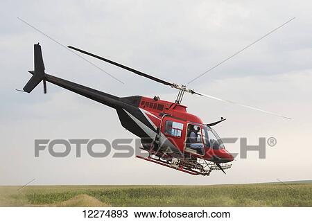 Stock Image - Crop dusting helicopter taking off from refilling for another flight; Iowa, United States of America. Fotosearch