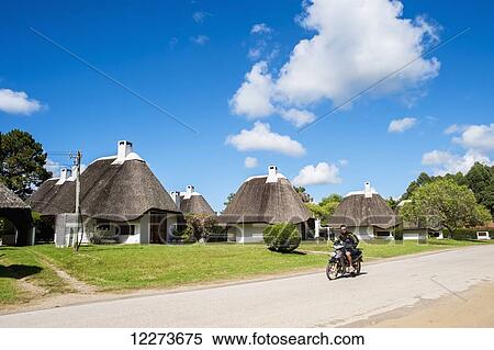 Stock Photography - Cycling down a road with traditional houses; La Pedrera, Uruguay. Fotosearch