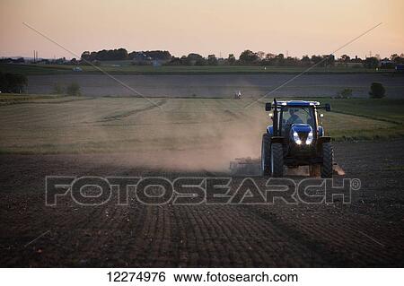 Stock Photograph - Disking field at sunset; New Holland, Pennsylvania, United States of America. Fotosearch