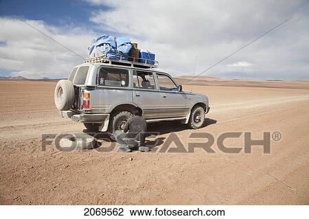 Stock Image - Driver Changing A Tire On A 4X4 Vehicle, Eduardo Avaroa National Park, Potosi Department, Bolivia. Fotosearch