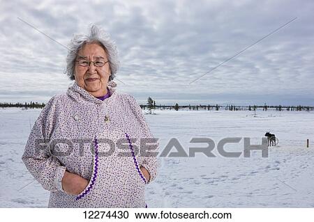 Elder Alaska native woman wearing a Kuspuk parka stands on snow covered tundra, Winter, Noatak, Arctic Alaska, USA View Large Photo Image Stock Image - Elder Alaska native woman wearing a Kuspuk parka stands on snow covered tundra, Winter, Noatak, Arctic Alaska, USA. Fotosearch