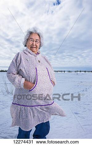 Elder Alaska native woman wearing a Kuspuk parka stands on snow covered tundra, Winter, Noatak, Arctic Alaska, USA View Large Photo Image Stock Image - Elder Alaska native woman wearing a Kuspuk parka stands on snow covered tundra, Winter, Noatak, Arctic Alaska, USA. Fotosearch
