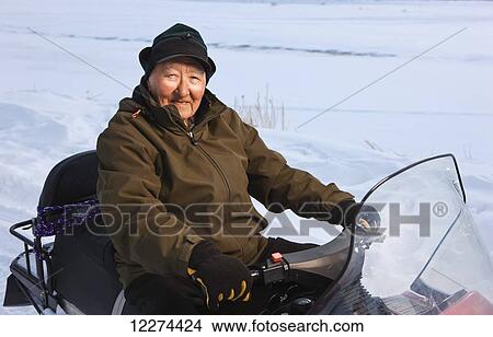 Elder Alaskan native man sits on a snow machine outside of Noatak, Arctic Alaska, winter View Large Photo Image Picture - Elder Alaskan native man sits on a snow machine outside of Noatak, Arctic Alaska, winter. Fotosearch
