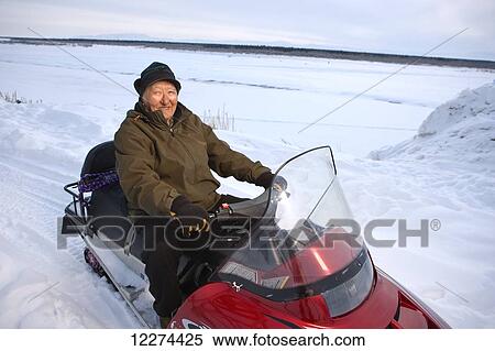 Elder Alaskan native man sits on a snow machine outside of Noatak, Arctic Alaska, winter View Large Photo Image Stock Photography - Elder Alaskan native man sits on a snow machine outside of Noatak, Arctic Alaska, winter. Fotosearch