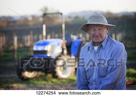 Elderly farmer in sun hat with new tractor in background; Paso Robles, California, United States of America View Large Photo Image Picture - Elderly farmer in sun hat with new tractor in background; Paso Robles, California, United States of America. Fotosearch