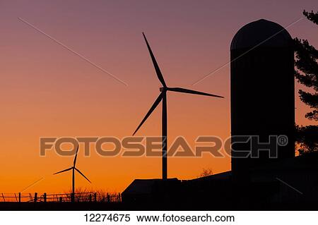 Stock Photography - Elk Wind Energy Farm and a silo at sunrise, near Edgewood; Iowa, United States of America. Fotosearch