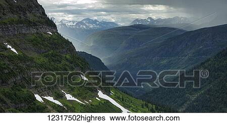 Stock Photograph - Extreme landscape of mountain range with steep slopes and traces of snow on lush foliage, Glacier National Park; Montana, United States of America. Fotosearch