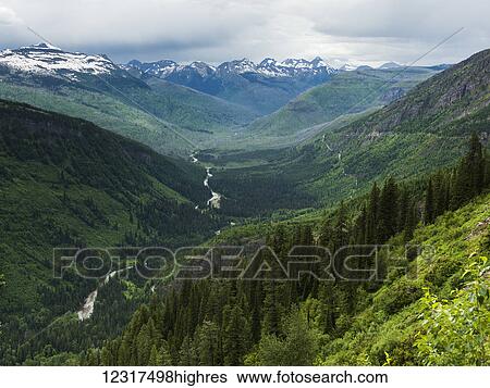 Stock Photograph - Extreme terrain of rugged mountains and green forested slopes, Glacier National Park; Montana, United States of America. Fotosearch