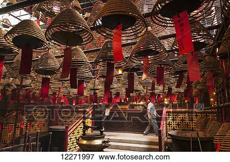 Stock Photo - Famous Man Mo Buddhist temple with spectacular incenses hanging from ceiling; Hong Kong, China. Fotosearch