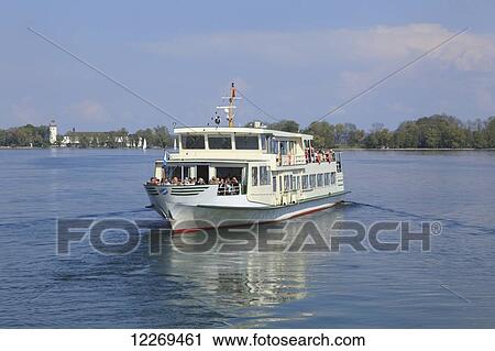 Stock Image - Ferry carries passengers across a lake; Chiemsee, Bayern, Germany. Fotosearch