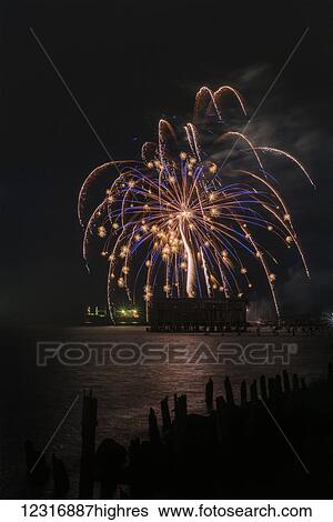 Stock Photograph - Fireworks brighten the nighttime sky; Astoria, Oregon, United States of America. Fotosearch