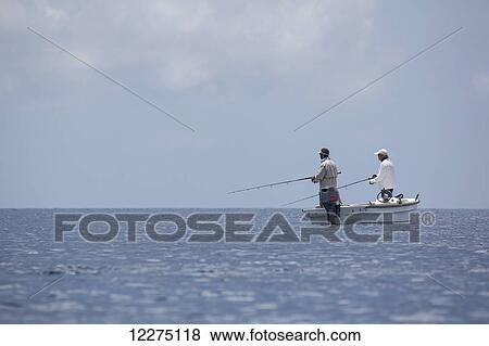 Stock Photo - Fishermen standing in a boat fishing; Tahiti. Fotosearch