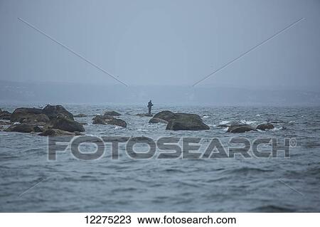 Fishing on the rocks in the water along the coast; Cape Cod, Massachusetts, United States of America View Large Photo Image Stock Image - Fishing on the rocks in the water along the coast; Cape Cod, Massachusetts, United States of America. Fotosearch