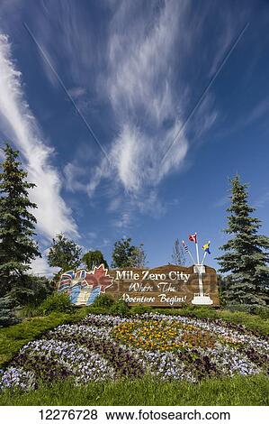 Stock Photo - Flags on the Mile Zero City Sign, the Start of Alaska Highway, Dawson Creek, British Columbia, Canada, Summer. Fotosearch