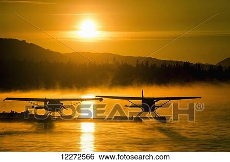Stock Photograph - Floatplanes silhouetted on Beluga Lake, Homer, Kenai Peninsula, Southcentral Alaska. Fotosearch