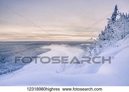 Stock Photograph - Fog rises off of the Copper River on a cold winter evening, warm sunset light casting Mount Drum into shadows in the background, Copper River Valley, South-central Alaska; Alaska, United States of America. Fotosearch