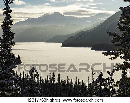 Stock Photograph - Frozen Muncho Lake in winter, Muncho Lake Provincial Park; British Columbia, Canada. Fotosearch