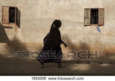 Full length of a woman walking on street against built structure in Bamako, Mali View Large Photo Image Stock Photo - Full length of a woman walking on street against built structure in Bamako, Mali. Fotosearch