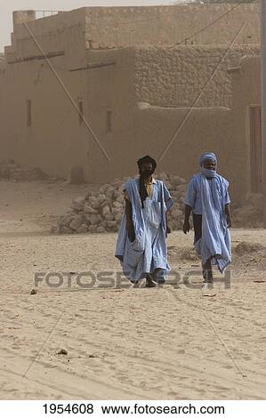 Stock Photo - Full length of Tuareg men walking against built structure in Timbuktu, Mali. Fotosearch