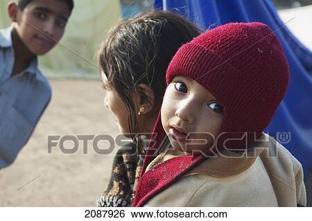 Stock Photograph - Girl Carrying A Baby In A Relief Camp After The 8 October 2005 Earthquake, Muzaffarabad, Azad Kashmir, Pakistan. Fotosearch