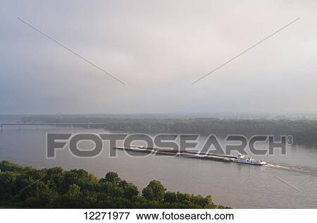 Stock Photo - Grain barge navigating the Mississippi River early on an overcast morning, near Hannibal; Missouri, United States of America. Fotosearch