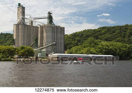 Stock Photography - Grain storage and a barge along the Mississippi River; McGregor, Iowa, United States of America. Fotosearch