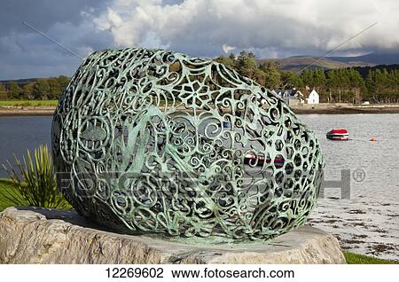 Stock Image - Green metal sculpture on a rock beside the beach; Kenmare, County Kerry, Ireland. Fotosearch