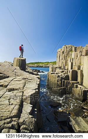 Stock Photograph - Hiker along basalt rock cliffs, Brier Island, Bay of Fundy; Nova Scotia, Canada. Fotosearch