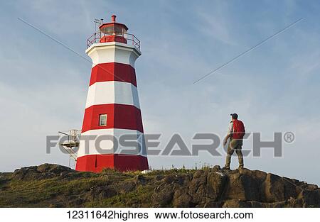 Stock Photograph - Hiker looking out over Brier Island Lighthouse, Brier Island, Bay of Fundy; Nova Scotia, Canada. Fotosearch