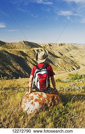 Stock Image - Hiker resting in South Saskatchewan River Valley near Beechy; Saskatchewan, Canada. Fotosearch