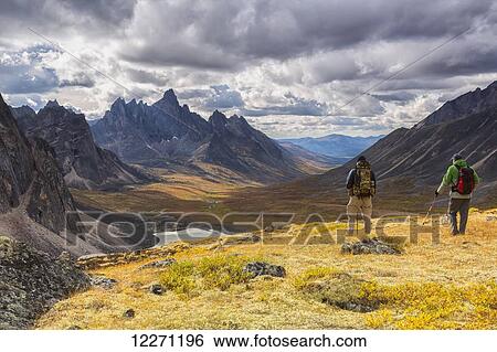 Hikers on an overlook viewing the beautiful autumn colours in Tombstone Territorial Park, with Tombstone Mountain in the distance; Yukon, Canada View Large Photo Image Stock Photograph - Hikers on an overlook viewing the beautiful autumn colours in Tombstone Territorial Park, with Tombstone Mountain in the distance; Yukon, Canada. Fotosearch