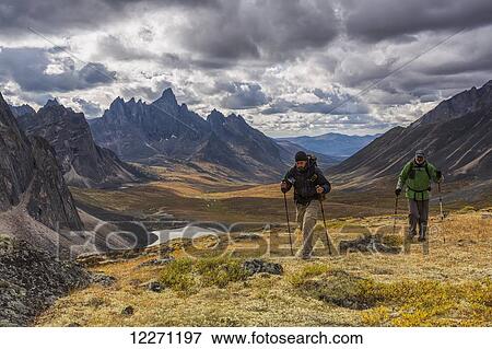 Stock Photo - Hikers walking along a ridge in Tombstone Territorial Park in autumn, with Tombstone Valley and Tombstone Mountain in the distance; Yukon, Canada. Fotosearch