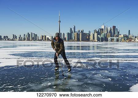Stock Image - Hockey player and city skyline from Ward's Island; Toronto, Ontario, Canada. Fotosearch
