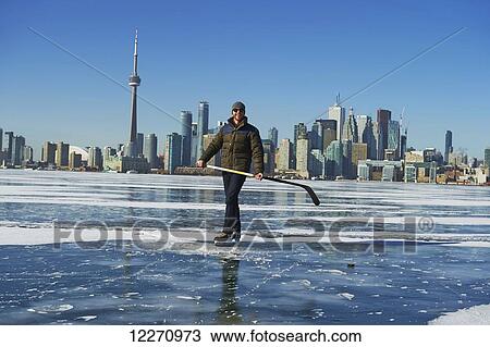 Stock Image - Hockey player and city skyline from Ward's Island; Toronto, Ontario, Canada. Fotosearch