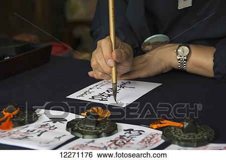 Stock Photograph - Japanese temple employee doing calligraphy; Uji, Kyoto, Japan. Fotosearch