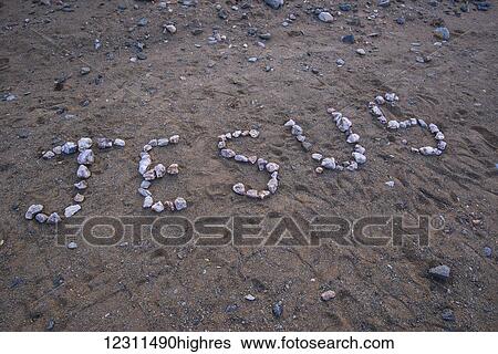 Stock Photograph - Jesus spelled out with rocks in the dirt; South Africa. Fotosearch