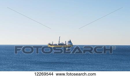 Picture - Large ship out in the mediterranean sea with a sailboat in front; Genoa, Liguria, Italy. Fotosearch