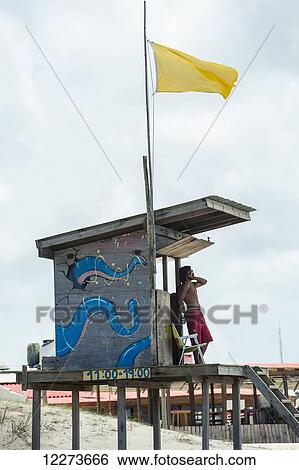 Stock Photograph - Lifeguard on duty at a lifeguarding station with a yellow flag; Valizas, Uruguay. Fotosearch